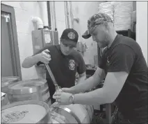  ?? STAFF PHOTOS BY DARWIN WEIGEL ?? Blue Dyer Distilling Co. owners Walker Dunbar, left, and Ryan Vierheller decant a sample of their first bourbon whiskey into a glass at their Waldorf distillery.