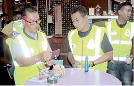  ??  ?? ACP Adzhar (left) inspecting documents of some of the 50 guest relations officers and masseuses during the raids in downtown Labuan in an effort to control crime and vice activities.