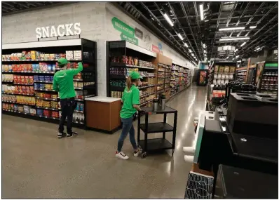  ?? (AP/Ted S. Warren) ?? Workers stock shelves and a coffee station Friday inside an Amazon Go Grocery store ahead of its opening in Seattle’s Capitol Hill neighborho­od.