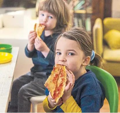  ?? JENNA MARIE WAKANI PHOTOS FOR THE TORONTO STAR ?? Ksenija Callaghan, 5, and Cash Callaghan, 2, nibble on pizza. The family subscribes to General Assembly Pizza for simpler dinners.