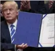 ?? PHOTO/ANDREW ?? President Donald Trump holds up one of four bills during a signing ceremony in the Roosevelt Room of the White House in Washington on Monday. AP
HARNIK