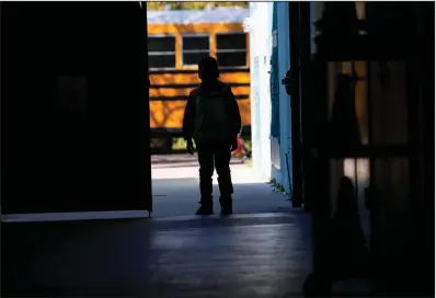  ?? (Miami Herald/Daniel A. Varela) ?? A child from a secret migrant camp in South Miami-Dade, Fla., is shown near a school bus recently. Most of the children at the camp had never been to school before an anguished school superinten­dent took charge without notifying federal authoritie­s.