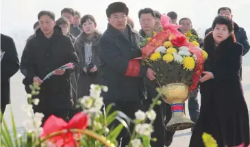  ??  ?? PAYING THEIR RESPECTS: People carry flowers to lay below the statues of former North Korean leaders Kim Il-sung and Kim Jong-il on Mansu Hill yesterday.