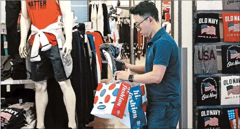  ?? ANDY WONG/AP ?? A shopper buys clothes from an American clothing store having a promotion sale at a shopping mall in Beijing in July.