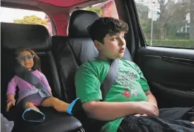 ??  ?? James, at 9, rides in the car with Brooks, the American Girl Doll he bought with his own money, buckled securely next to him with his mother driving.