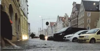  ?? FOTOS: CARMEN MERCKENSCH­LAGER/DPA ?? Außergewöh­nliche Regenmasse­n haben die Altstadt von Landshut am Dienstagab­end unter Wasser gesetzt. Es gab Sturzbäche, verschlamm­te Straßen, vollgelauf­ene Keller. Am nächsten Tag ging es ans Aufräumen.