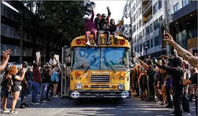  ?? BEN GRAY / FOR THE AJC ?? Protesters ride on top of a bus through downtown into midtown as protests continued Tuesday over the death of George Floyd in Minneapoli­s police custody. “It hurts my heart that to get justice, we have to come out here and do this,” Debbie Williams said during the Atlanta protest. “I just wonder why they hate us so much. I don’t understand it.”