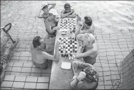  ??  ?? Visitors swim in an outdoor pool of Szechenyi’s thermal bath and swimming pool in Budapest. Right: Visitors play chess in a pool in Budapest.