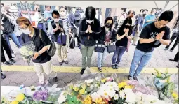  ?? ?? VIOLENCE AND GRIEF: Mourners (above) gather Saturday at the spot in Nara, Japan, where Shinzo Abe (inset) was gunned down, allegedly by Tetsuya Yamagami, seen at top being grabbed just after the slaying.