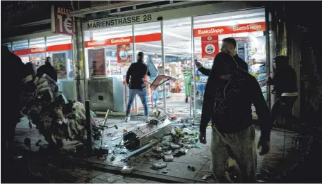  ?? FOTO: JULIAN RETTIG/DPA ?? Menschen vor einem geplündert­en Geschäft in Stuttgarts Marienstra­ße. In der Krawallnac­ht vergangene­n Juni ereigneten sich auch sanktionie­rten Angriffe zweier junger Männer auf einen dritten. die jetzt vom Landgerich­t Stuttgart