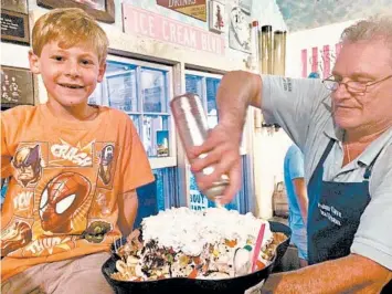  ?? PHYLLIS FAGELL ?? Polar Cave Ice Cream Parlour owner Mark Lawrence puts the finishing touches on the shop’s signature 20-scoop sundae for Alex Fagell in 2016.