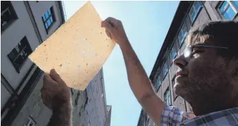  ?? FOTO: DPA ?? Klaus Wengenmayr rückt sein Büttenpapi­er ins rechte Licht: handgeschö­pft, mit Wasserzeic­hen.