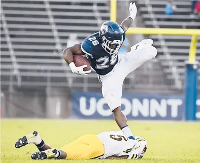  ?? PHOTOS BY JESSICA HILL/SPECIAL TO THE COURANT ?? UConn’s Nathan Carter leaps over Wyoming’s Esaias Gandy in the second half Saturday at Pratt & Whitney Stadium at Rentschler Field in East Hartford. The Huskies lost 24-22.