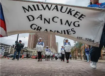  ?? (AP Photo/kenny Yoo) ?? A banner for the Milwaukee Dancing Grannies flutters in the wind as the Grannies march in a Veterans’ Day parade on Nov. 5 in Milwaukee. The group dances to a number of songs, including “We Are Family,” “Pretty Woman” and “Old Time Rock and Roll.” They also have special routines and songs for holidays.