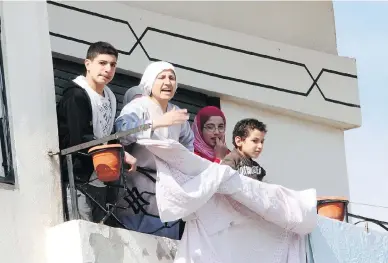  ?? ANWAR AMRO / AFP / GETTY IMAGES ?? A Syrian family stands on the balcony of their flat in the town of Daraa in southern Syria in March 2011 as the demonstrat­ions against President Bashar Assad began. Daraa is known as the birthplace of the Syrian revolution.