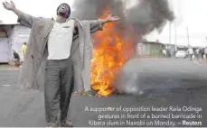  ?? — Reuters ?? A supporter of opposition leader Raila Odinga gestures in front of a burned barricade in Kibera slum in Nairobi on Monday.