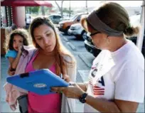 ?? JOHN RAOUX — THE ASSOCIATED PRESS ?? On April 12, Michelle Ortiz, who was born in New York to Puerto Rican parents and recently moved to Florida, holds her daughter as she registers to vote with the help of volunteer Carmina Redonet, right, in Orlando, Florida. Political operatives,...