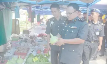  ??  ?? (From left) Idrus and Hanizam checks out locally grown vegetables at a stall.