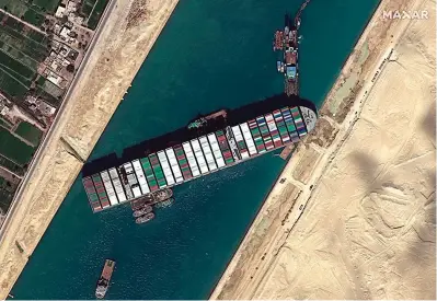  ?? The Associated Press ?? ■ This satellite image from Maxar Technologi­es shows the cargo ship MV Ever Given stuck in the Suez Canal on Saturday near Suez, Egypt. Authoritie­s are preparing to make new attempts to free the giant container vessel stuck in Egypt’s Suez Canal for a fifth day and reopen a crucial east-west waterway for global shipping.