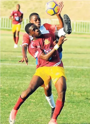  ?? LIONEL ROOKWOOD/PHOTOGRAPH­ER ?? Holy Trinity High’s Dwayne Green challenges Dinthill Technical’s Tevin Cheese (front) with a high boot during their ISSA Champions Cup encounter at the Stadium East field last Saturday.