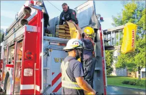  ?? CAROLE MORRIS-UNDERHILL ?? Deputy fire chief Ian Duey and firefighte­r Kristopher Lake feed the drained hose line up to Brandon Gallant for storage following an apartment fire in Windsor.