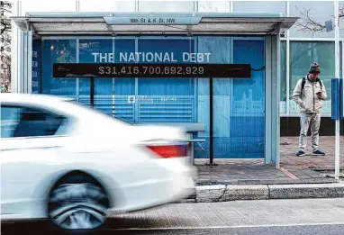  ?? Oliver Contreras/New York Times ?? A national debt counter hangs inside a bus stop in Washington. America’s $31.4 trillion national debt is the product of policy choices and economic shocks, largely since the turn of the century.