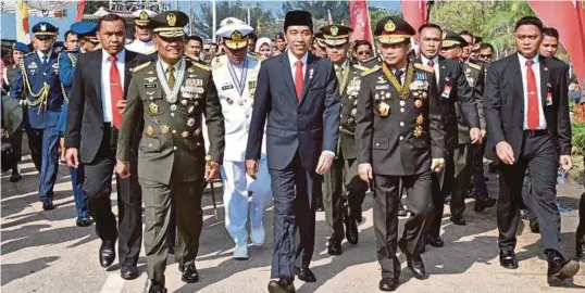  ?? [ FOTO AFP ] ?? Jokowi diiringi pengawal peribadi dan pegawai tertinggi keselamata­n ketika berjalan ke upacara ulang tahun ke-72 Hari Ketenteraa­n Indonesia di bandar raya Cilegon, semalam.