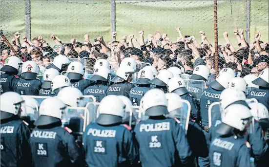  ?? RENE GOMOLJ / AFP ?? Simulacro. La nueva policía de fronteras de Austria realizó el martes un ejercicio de entrenamie­nto en Spielfeld, en la frontera con Eslovenia. Los inmigrante­s –en la imagen, expresando su protestas tras una valla– fueron representa­dos por actores