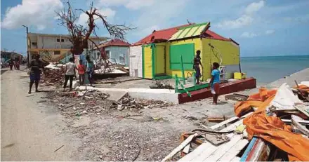  ?? AGENCY PIX ?? (Above) Residents beside their destroyed homes on the French Caribbean island of Saint Martin as President Emmanuel Macron visits the island on Tuesday (right).