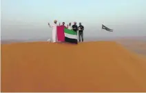  ?? Courtesy UAE Adventure Club ?? The adventurer­s and their guide fly the UAE flag atop Ramlet Jadilah in Oman after a 1,400-kilometre journey.