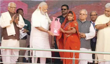  ?? — PTI ?? Prime Minister Narendra Modi presents cooking gas connection to a woman of a Below Poverty Line family during the launch of the Pradhan Mantri Ujjwala Yojana in Ballia on May 1, 2016