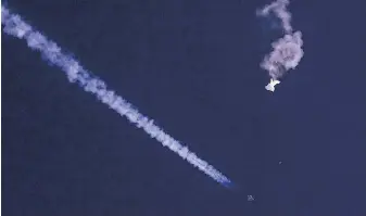  ?? CHAD FISH VIA THE ASSOCIATED PRESS ?? The remnants of a Chinese balloon drift above the Atlantic Ocean, just off the coast of South Carolina, with a fighter jet and its contrail seen below it on Feb. 4.