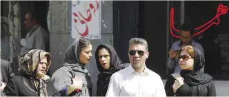  ?? — AFP ?? Iranians walk past election posters of President Hassan Rouhani, who is running in the presidenti­al elections, in Tehran yesterday.