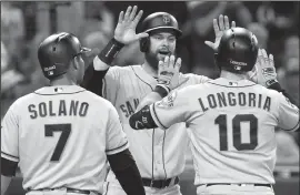  ?? HAYNE PALMOUR IV/TRIBUNE NEWS SERVICE ?? The Giants' Brandon Belt, middle, and Donovan Solano (7) celebrate a three-run home run by Evan Longoria (10) against the Padres in San Diego on Tuesday.