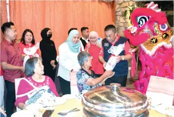  ?? Photo — Bernama ?? Suhaili (right) and Siti Ayu (third right) distributi­ng food packages and festive hampers to the recipients.