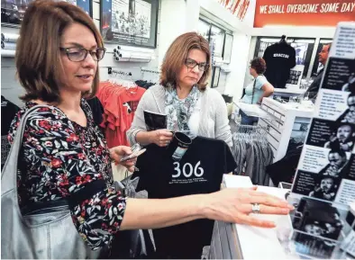  ??  ?? During a trip to the National Civil Rights Museum, twin sisters Tracy Bouslog, left, and Terri Fisher-Reed look over MLK50 merchandis­e, including a “306” T-shirt, reference the room Dr. Martin Luther King Jr. was staying in when he was killed outside...