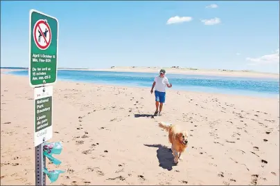  ?? JIM DAY/THE GUARDIAN ?? Rick Garrett walks his dog Bauwer on Parks Canada property near Tracadie Beach. Garrett claims dogs should be allowed on Parks Canada beaches below the high water mark.