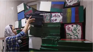  ?? PICTURE: AP PHOTO/RAHMAT GUL ?? MEMORIES: Zahra Hossaini, a member of the Afghanista­n Human Rights and Democracy Organizati­on, arranges ‘memory boxes’ among some 300 stored in Kabul. Survivors of Afghanista­n’s many wars have tucked memories of those they have lost inside boxes draped...