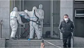  ?? (AFP) ?? Medical staff members carry a patient into the Jinyintan hospital, where patients infected by a mysterious SARS-like virus are being treated, in Wuhan in China’s central Hubei province on Saturday