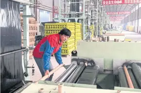  ??  ?? A HELPING HAND: Yan Xiaoling operates a machine that chops up plastic mulch for greenhouse­s at a government-subsidised factory in Tongwei, Gansu province.