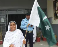  ?? AFP ?? A woman walks out of a polling station holding national flag after casting her ballot in Rawalpindi. —