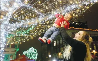  ?? (NWA Democrat-Gazette File Photo/David Gottschalk) ?? Tabitha Westbrook lifts her son Kye Williams, 9 months, up to see lights suspended in the trees at last year's Lights of the Ozarks display in downtown Fayettevil­le. The lights illuminate the square daily from 5 p.m. to 1 a.m. and will remain on display through Dec. 31.