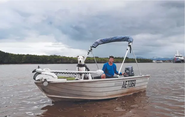  ?? Picture: STEWART McLEAN ?? CLOUDS LOOMING: Daniel Miller, of Woree, and his dog Luxy head out in Chinaman Creek for a spot of fishing despite the damp weather.