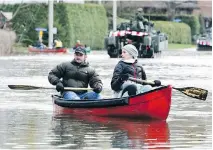  ?? JOHN MAHONEY ?? A couple paddles on du Lac Blvd. in Deux-Montagnes as army personnel deliver sandbags on May 8. Quebec has few up-to-date flood-plain maps, and fails to regularly monitor water levels.