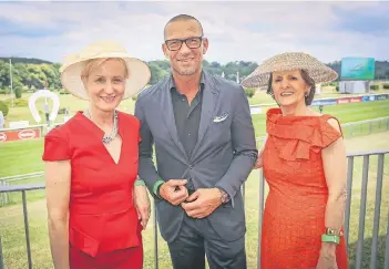  ?? RP-FOTO : H.-J. BAUER ?? Stilecht und mit Hut gut geschützt vor der Sonne kamen die Modeexpert­in Monika Gottlieb (r.) und Marion Bock (Galderma) auf die Pferderenn­bahn. Andreas Rebbelmund (Breuninger) ließ sich gerne von den Ladys einrahmen.