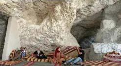  ??  ?? Ahmed Amarneh (right), and family members sit on cushions at his home built in cave.