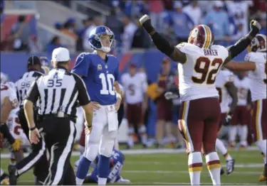  ?? BILL KOSTROUN — ASSOCIATED PRESS ?? Giants quarterbac­k Eli Manning and Washington Redskins’ Chris Baker react after Manning threw an intercepti­on during the second half of Washington’s 29-27 win at East Rutherford, N.J., on Sunday.