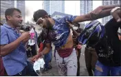  ?? ERANGA JAYAWARDEN­A — THE ASSOCIATED PRESS ?? Anti-government protesters help a fellow protester who was beaten up by government supporters during a clash in Colombo, Sri Lanka, on Monday.