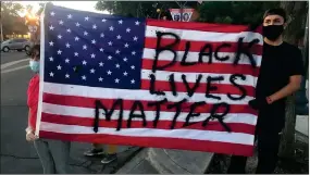  ?? RECORDER PHOTO BY CHARLES WHISNAND ?? Eduardo Bermudez holds with another protestor an American Flag with “Black Lives Matter” printed on it on Saturday, May 30, 2020.