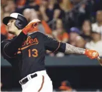  ?? AP ?? Manny Machado extiende sus brazos y observa la dirección de la pelota en el grand slam que produjo anoche y que definió el choque para los Orioles.